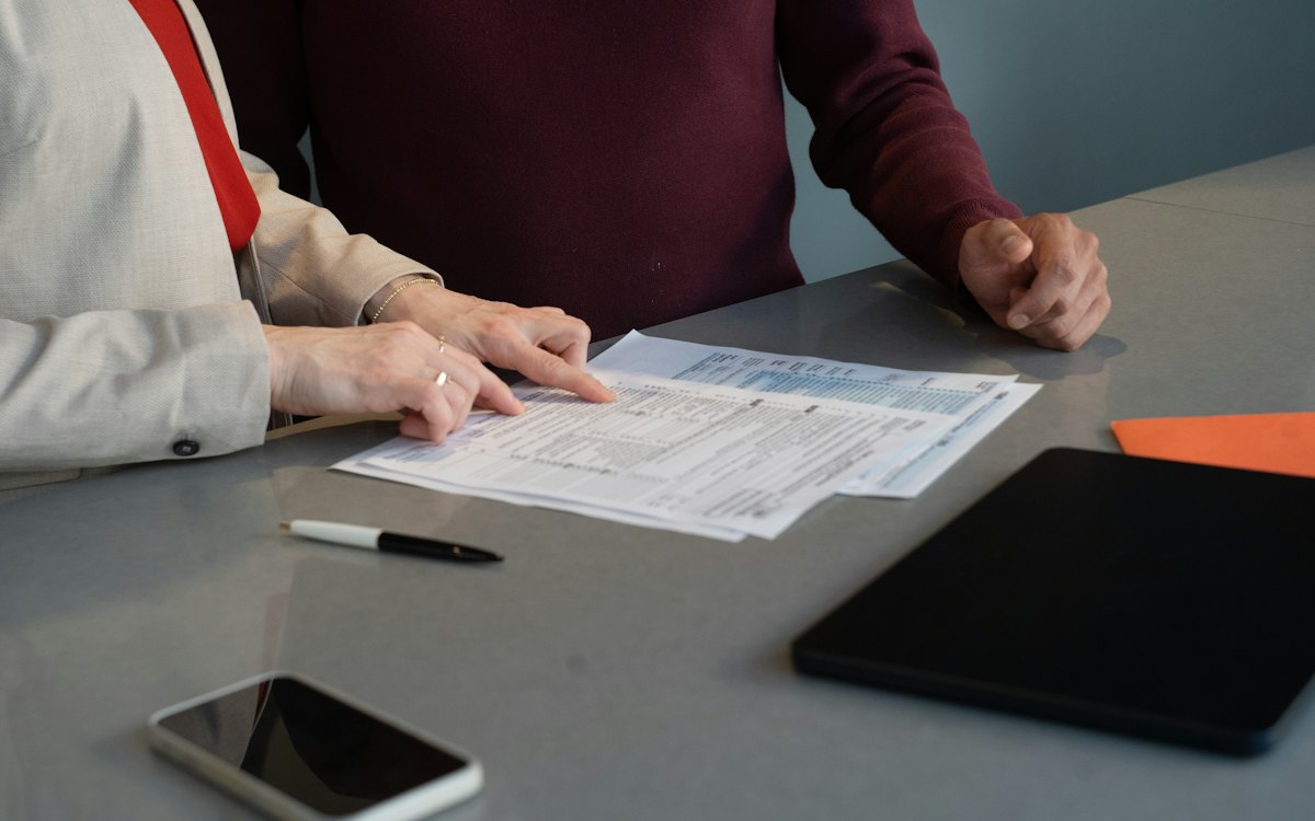 Duas pessoas conferindo documentos sobre a mesa