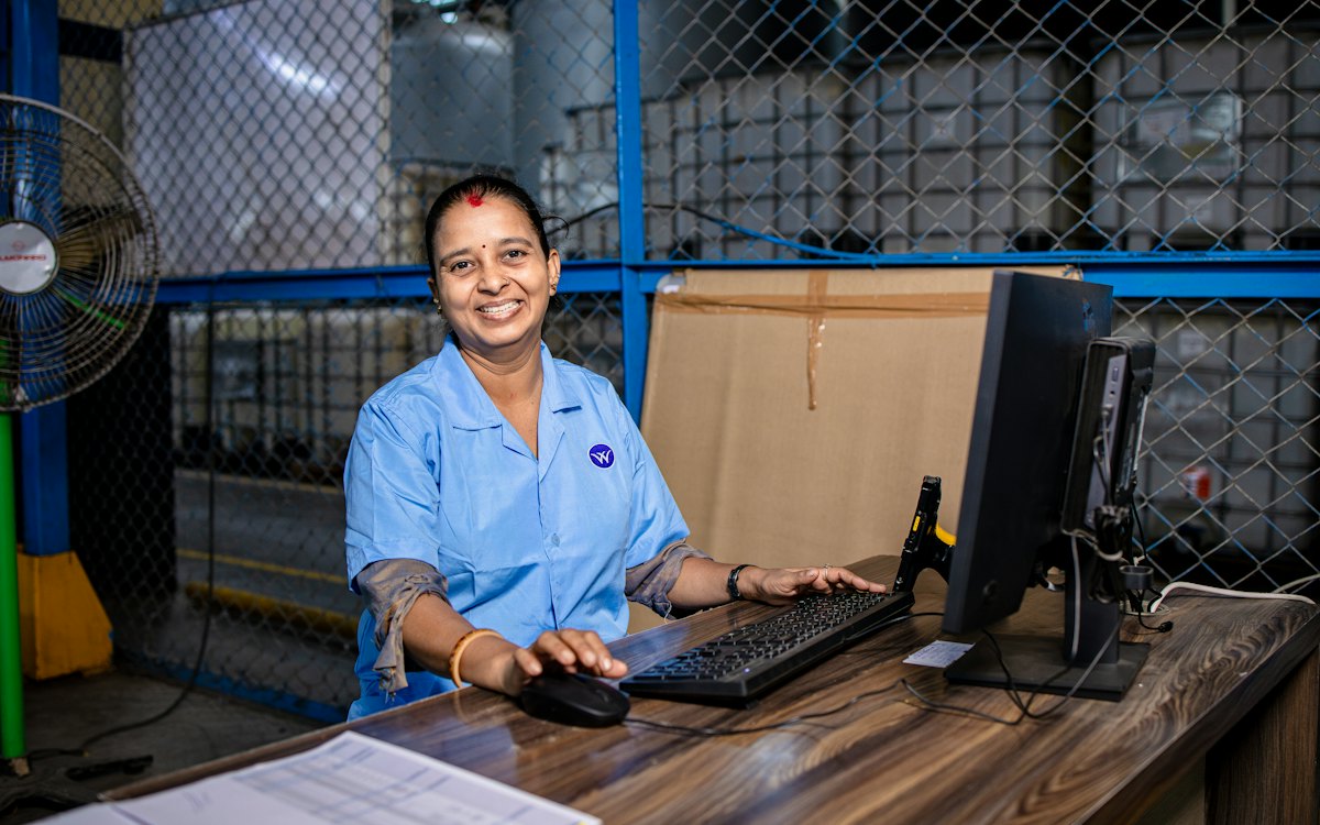 Trabalhadora em uma bancada de fábrica diante do computador