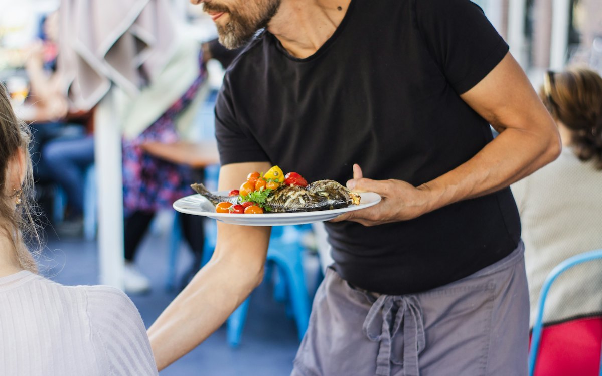 Garçom servindo um prato em um restaurante