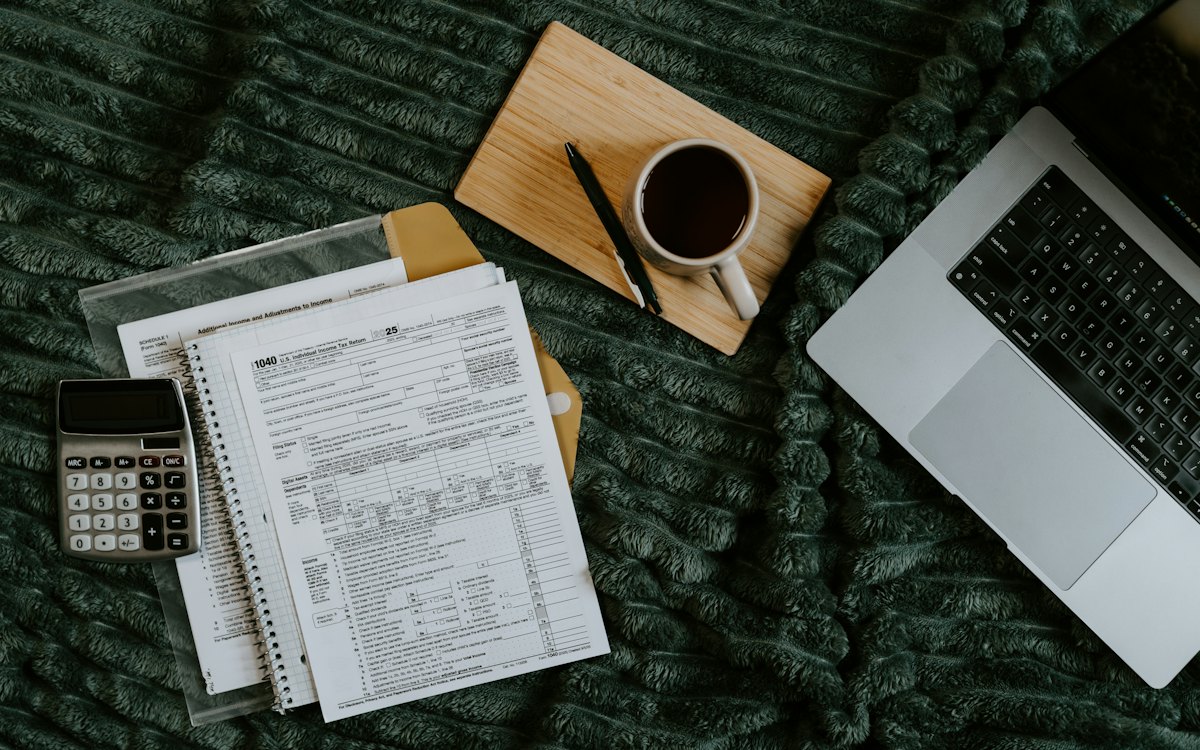Notebook, notas fiscais e calculadora sobre uma manta