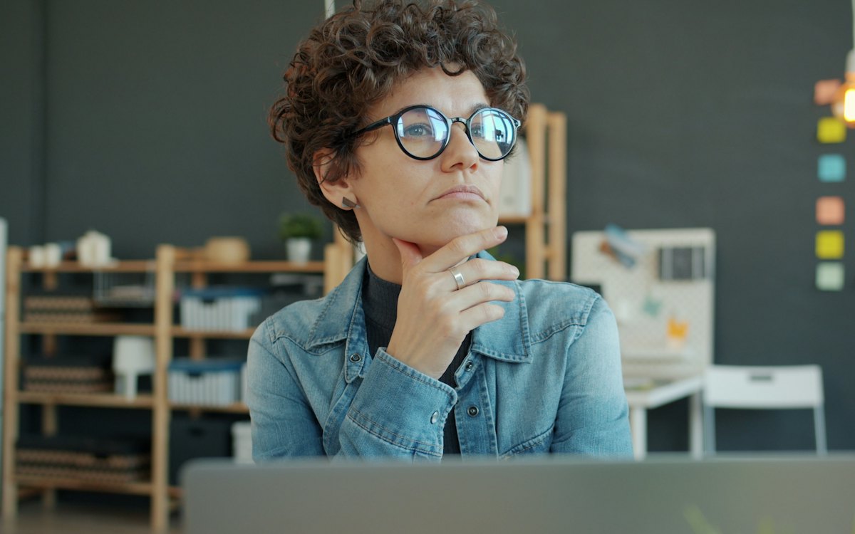 Mulher pensativa diante do computador no escritório