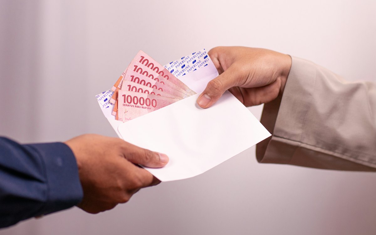 Mãos entregando um envelope com dinheiro